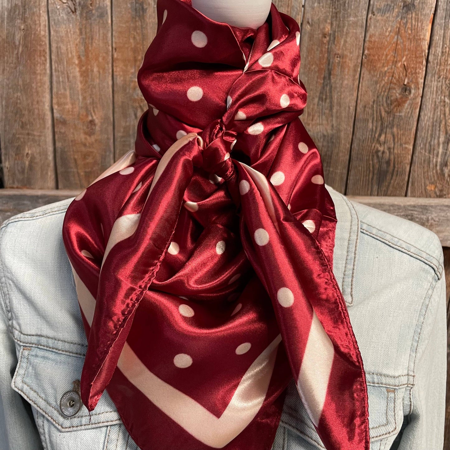 Red polka dot scarf draped over a light blue denim jacket