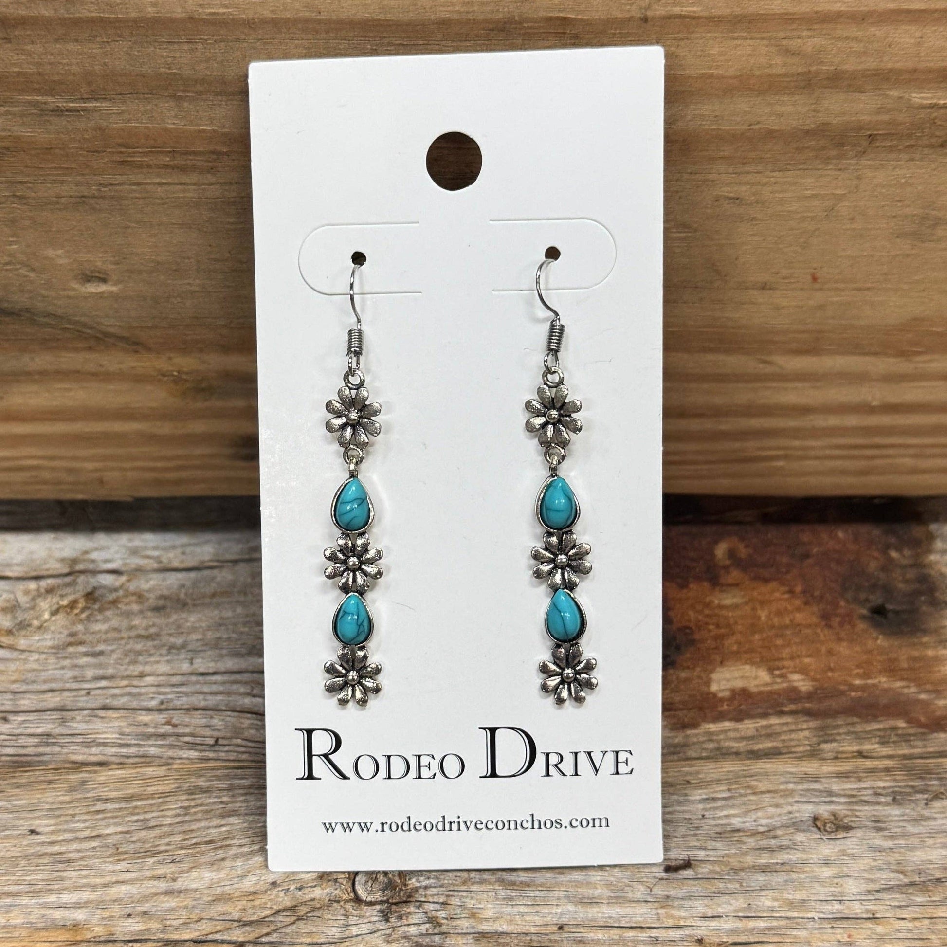 Silver-plated floral western earrings with turquoise teardrop accents and fish hook posts, perfect for cowgirl, western, and boho fashion.