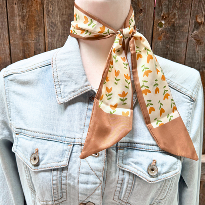 Mannequin wearing a denim jacket with a patterned scarf draped over the head against a wooden background