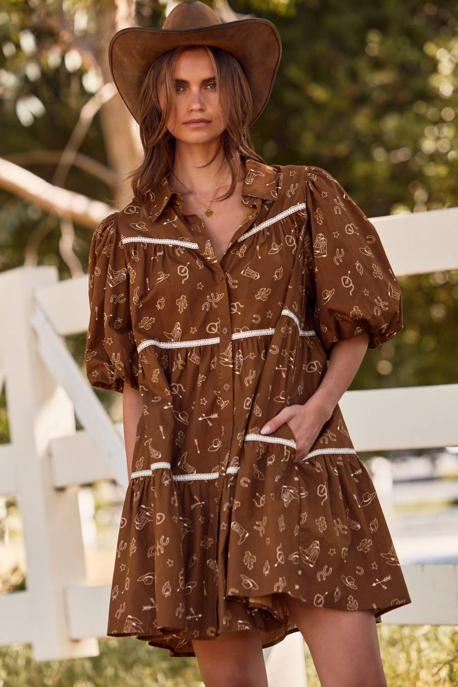 Woman wearing a brown patterned dress and hat outdoors